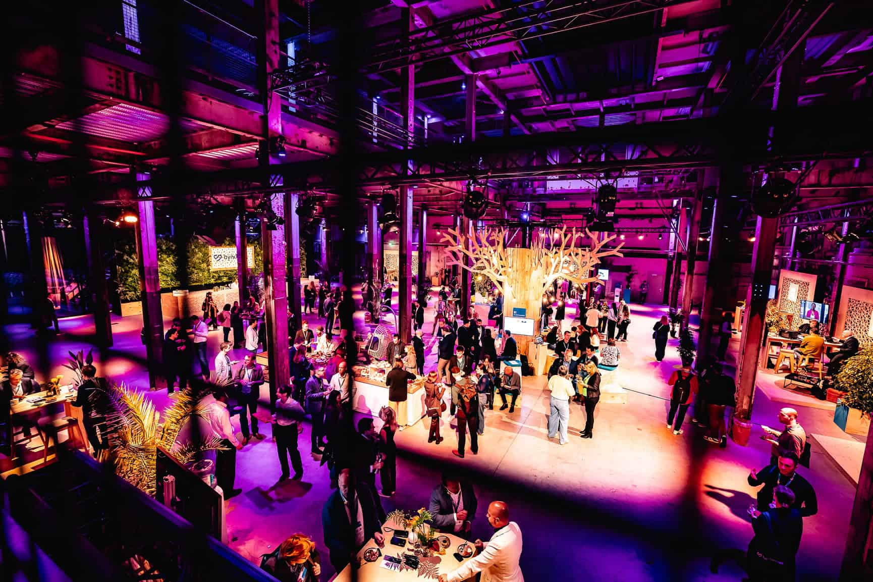 Evenementruimte in de Middenfabriek met kleurrijk licht en bezoekers.